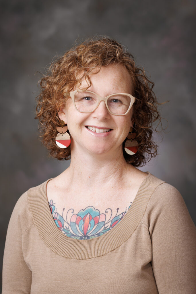 woman with curly red hair and tan shirt